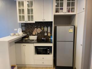 a small kitchen with white cabinets and a refrigerator at The Patio bangsaen miracle Seaview in Ban Bang Saen (1)