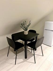Una mesa negra con dos sillas y un jarrón. en Ny og moderne 2-roms leilighet en Bodø