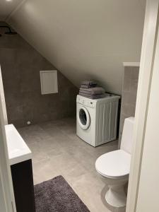 a bathroom with a toilet and a washing machine at Ny og moderne 2-roms leilighet in Bodø