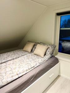 Cama en habitación pequeña con ventana en Ny og moderne 2-roms leilighet en Bodø