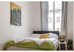 a bedroom with a bed with a green blanket and a window at Viennese 3BR shared Apt. Near Wiener Stadthalle & Central in Vienna
