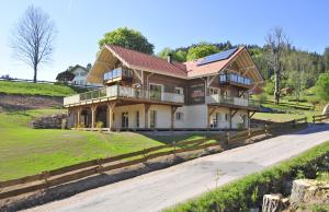 een groot huis op een heuvel met een oprit bij Chambres d'hôtes Couleurs Bois & Spa in Xonrupt-Longemer