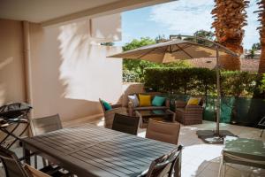 a patio with a wooden table and chairs and an umbrella at Martine & Thomas Santa Lucia in Saint-Raphaël