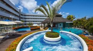 une piscine dans un complexe avec un palmier au milieu dans l'établissement Blue Marlin Cotovelo - Vista Vale - Reformado, à Parnamirim