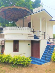 a small house with blue stairs and an umbrella at Jungle Villa Munnar in Pooppara