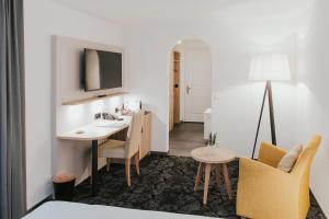 una camera d'albergo con scrivania, tavolo e sedie di Gartenhaus by Ochsen Lenzburg a Lenzburg