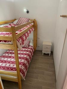 a bedroom with two bunk beds and a night stand at Appartement lumineux aux pieds des pistes in Saint-François-Longchamp