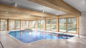 a large swimming pool with glass windows in a house at Arber Resort & Wellness Šumava in Železná Ruda
