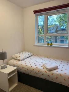 a small bedroom with a bed and a window at Cheerful 4-bedroom house with multiple car parking in Manchester