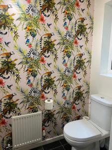 a bathroom with a toilet and a wallpaper with birds at Cheerful 4-bedroom house with multiple car parking in Manchester