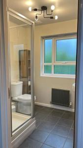 a bathroom with a toilet and a window at Cheerful 4-bedroom house with multiple car parking in Manchester