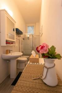 un baño con lavabo y un jarrón con una rosa. en La dimora di Amélie-Self Check in-Parcheggio gratuito, en San Lazzaro di Savena