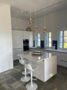 a kitchen with a large island with two white chairs at Kalymnos, très belle villa avec vue sur la mer in Kalymnos