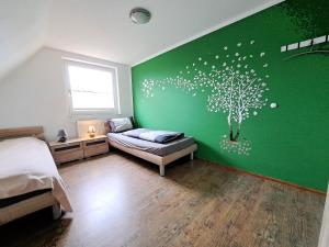 Ferienwohnung في Neukirchen: غرفة نوم بها جدار أخضر مع شجرة مرسومة عليها