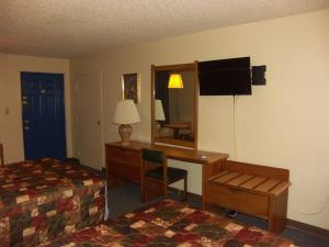 Habitación de hotel con escritorio, cama y espejo en Deerwood Inn & Madison Campground, en Madison