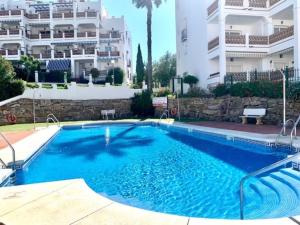 a large blue swimming pool in front of a building at Sunset apartment, front line Mijas Golf in Mijas