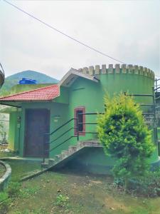 a small green house with a staircase in front of it at Jungle Villa Munnar in Pooppara