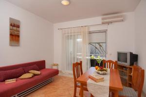 a living room with a red couch and a table at House Marta in Baška Voda