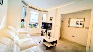 a living room with a white couch and a table at Surbiton Luxury Garden House 19 in Surbiton
