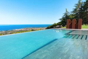 a swimming pool with chairs and the ocean in the background at Tenuta della Contea in Mascali