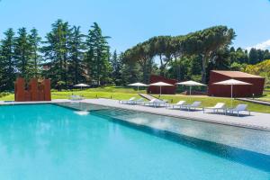 a large swimming pool with lounge chairs and umbrellas at Tenuta della Contea in Mascali