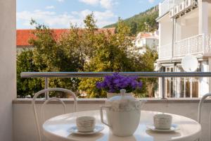 a table with two cups and a vase with purple flowers at House Marta in Baška Voda