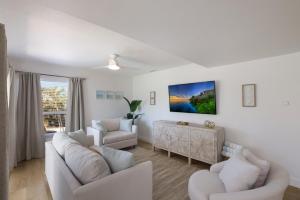 a living room with white furniture and a large window at Hidden Pearl home in Holmes Beach