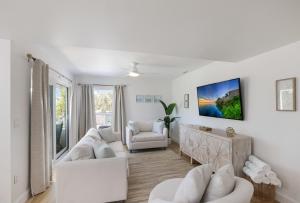 a living room with white furniture and a large window at Hidden Pearl home in Holmes Beach