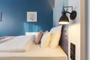 Schlafzimmer mit blauen Wänden und einem Bett mit Kissen in der Unterkunft Yggotel Solsort in Essen