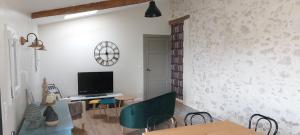 ein Wohnzimmer mit einem TV, einem Tisch und Stühlen in der Unterkunft Le Poutic piscine chauffee in Créon-dʼArmagnac