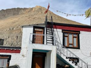 a house with a staircase in front of a mountain at SpitiDiaries Homestay in Kaza