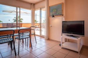 a living room with a television and a table with chairs at AT019 Les Palmeres in Torredembarra