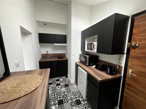 eine kleine Küche mit schwarzen Schränken und einer Mikrowelle in der Unterkunft Le Lyautey - Appart neuf centre-ville Châteaudun in Châteaudun