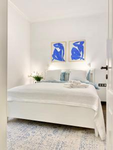 a white bedroom with a large white bed with blue paintings at Vintage Top Centre Apartment in Sofia