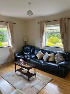 a living room with a black leather couch and a coffee table at ChestNut View Oldcastle 1 bed-room self catering in Oldcastle