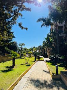 a walkway through a park with palm trees at Los Jardines Isla Canela in Huelva