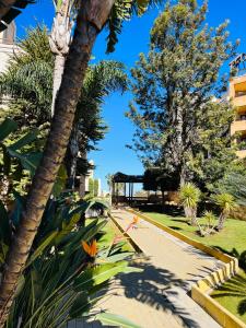un parque con palmeras y una acera en Los Jardines Isla Canela, en Huelva