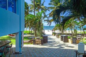 a beach with palm trees and chairs and the ocean at c3 Cowrie Shell Residences in Mombasa