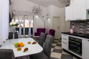 a kitchen with a white table with fruit on it at Apartments Zdeslav in Rogoznica