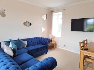 a living room with a blue couch and a tv at Bogrie Cottage in Canonbie