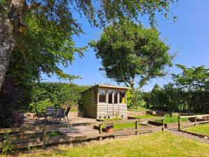 a small cabin in the middle of a garden at Bogrie Cottage in Canonbie