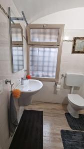 een badkamer met een wastafel, een toilet en een raam bij Beautifully restored romantic apartment in the centre of historic Dolcedo in Dolcedo