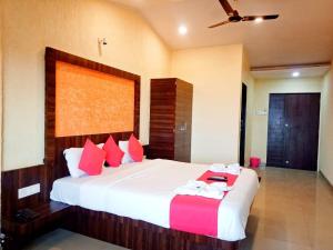 a bedroom with a large white bed with red pillows at Shivneri Holiday Resort in Mahabaleshwar