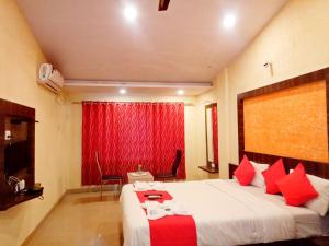 a bedroom with a large bed with red pillows at Shivneri Holiday Resort in Mahabaleshwar