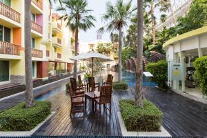 an outdoor patio with tables and chairs and palm trees at Mykonos Condo in Hua Hin