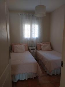 two beds in a small room with a window at Aldea Playa Golf 2 dormitorios in Huelva