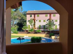 uma vista para uma piscina a partir de uma janela em Aldea Playa Golf 2 dormitorios em Huelva