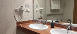 a bathroom with two sinks and a hair dryer at Hotel Travessera in Barcelona +69 photos