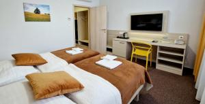 a hotel room with two beds and a desk and a television at Hotel Kristína in Dubnica nad Váhom