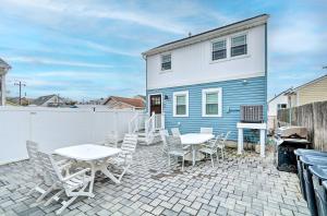a patio with tables and chairs in front of a blue and white house at Modern Townhome Walk to Beach, Bars and Eats! in Seaside Heights